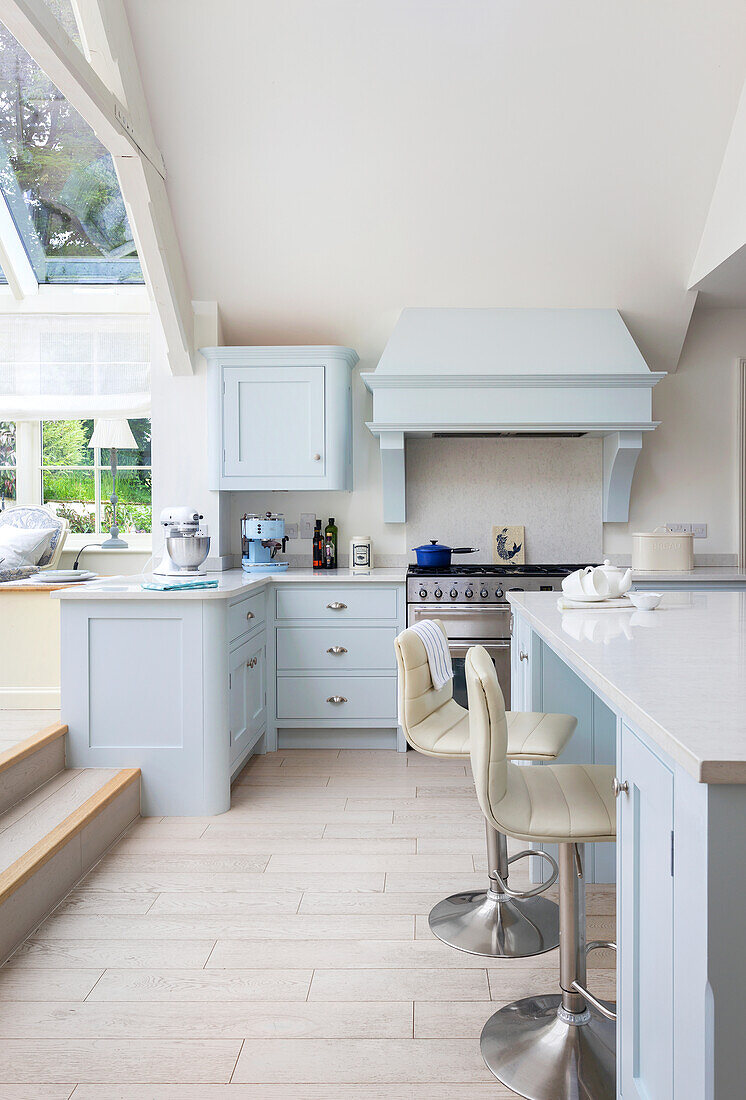 Bright kitchen with light blue cabinets and bar stools at a white island