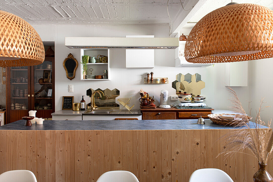 Open-plan kitchen with kitchen island and woven rattan hanging lamps