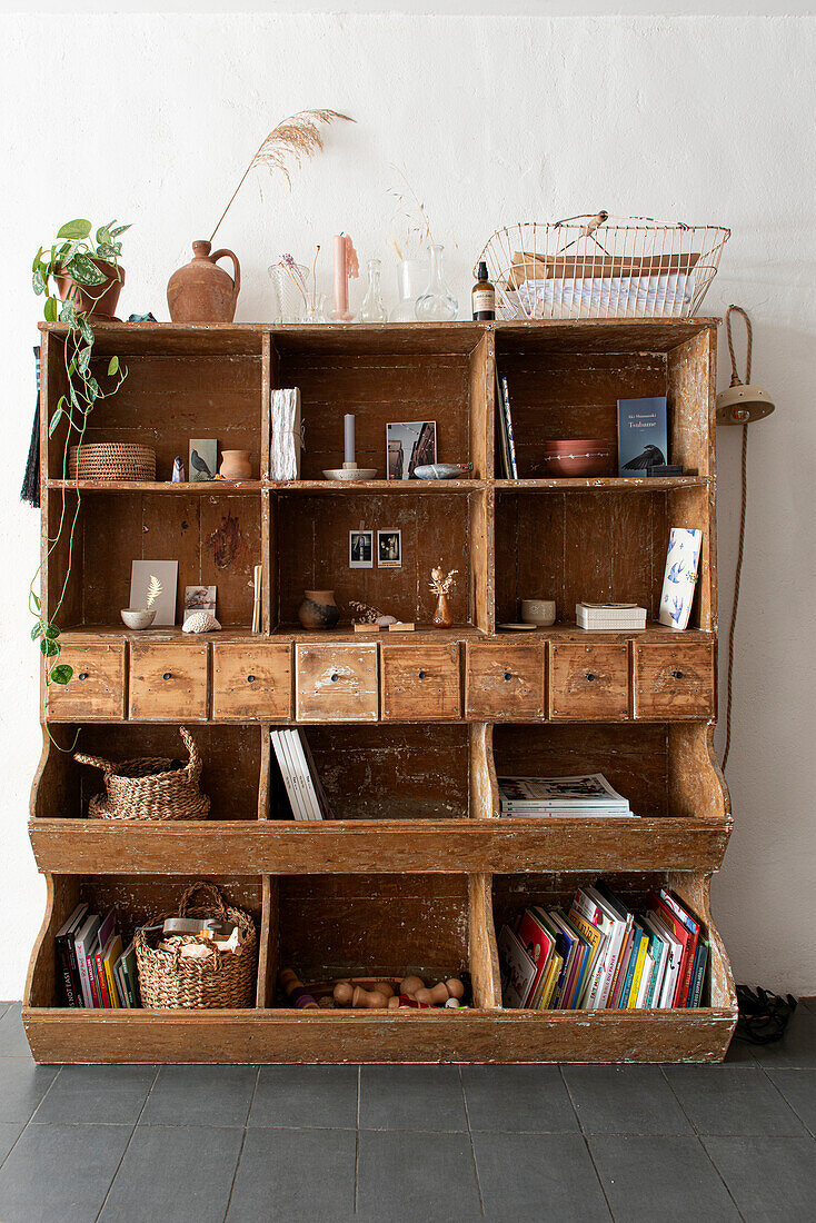 Offener Vintage-Holzschrank mit Fächern und Schubladen, Bücher und Deko-Objekte im Vintage-Stil
