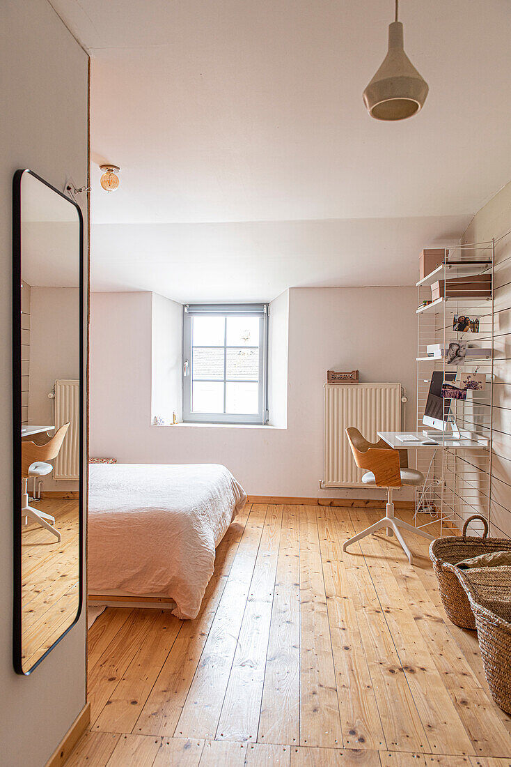 Schlafzimmer mit Arbeitsplatz, Holzboden und pastellfarbenen Wänden