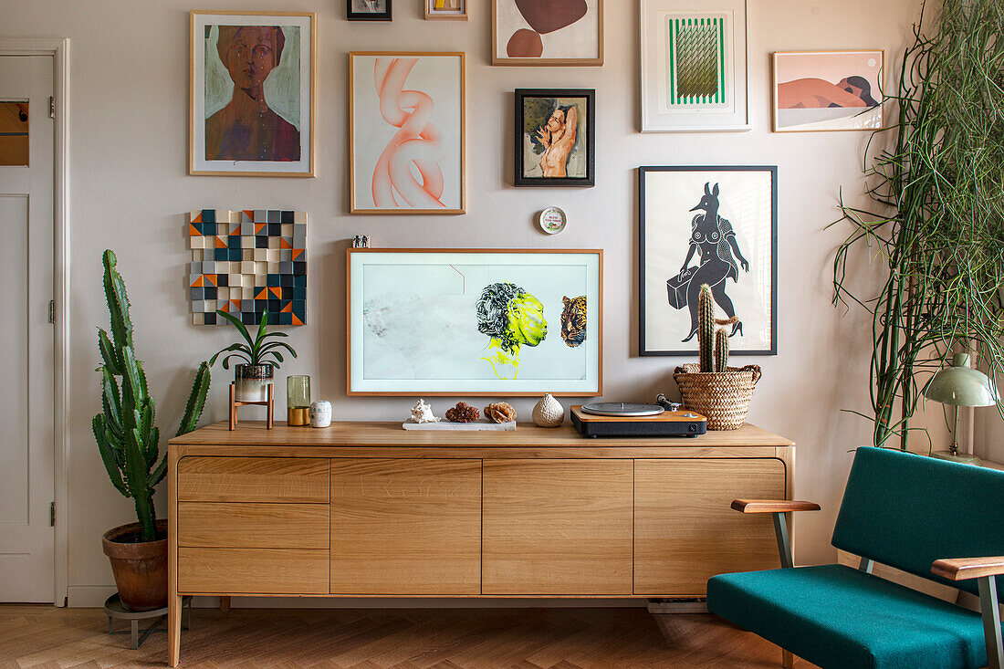 Sideboard mit Kunstdrucken und Pflanzen in modernem Wohnzimmer