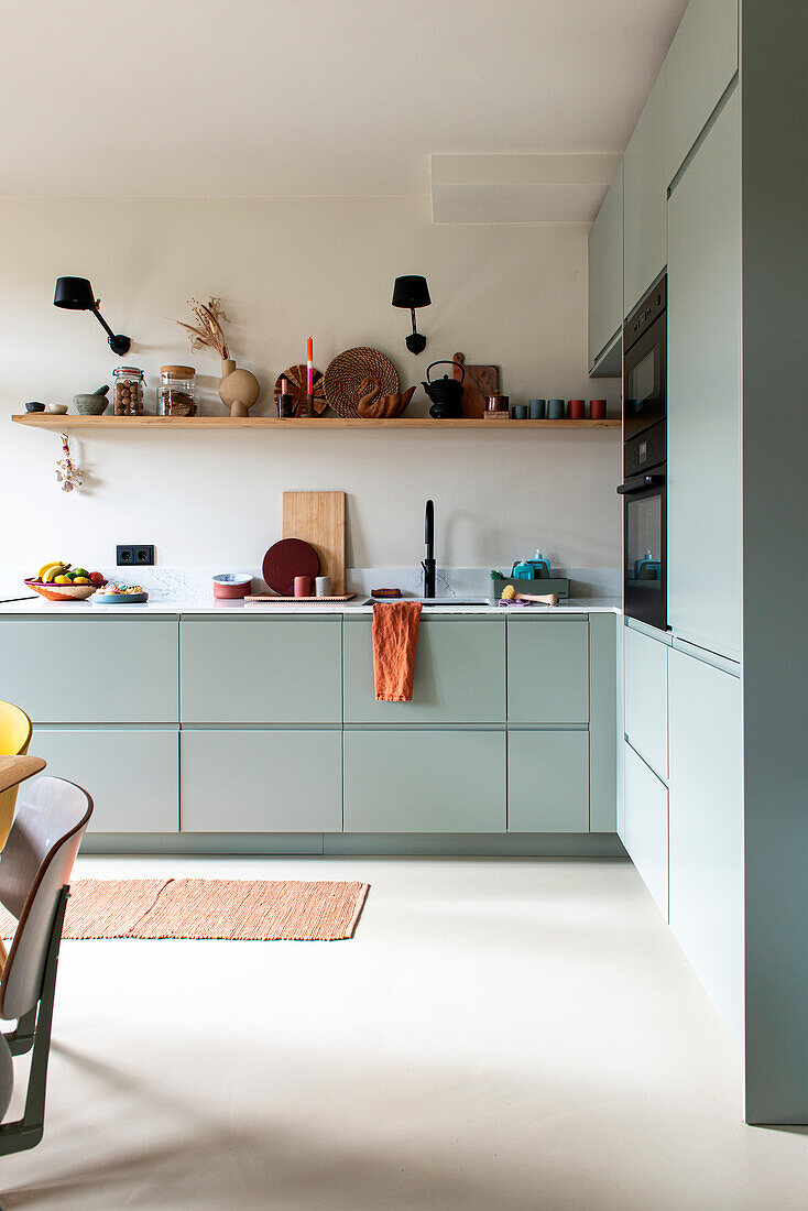 Modern kitchen in green with open shelves and black wall lamps