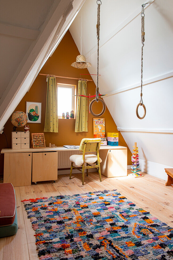 Attic children's room with desk, gymnastic rings and colorful carpet