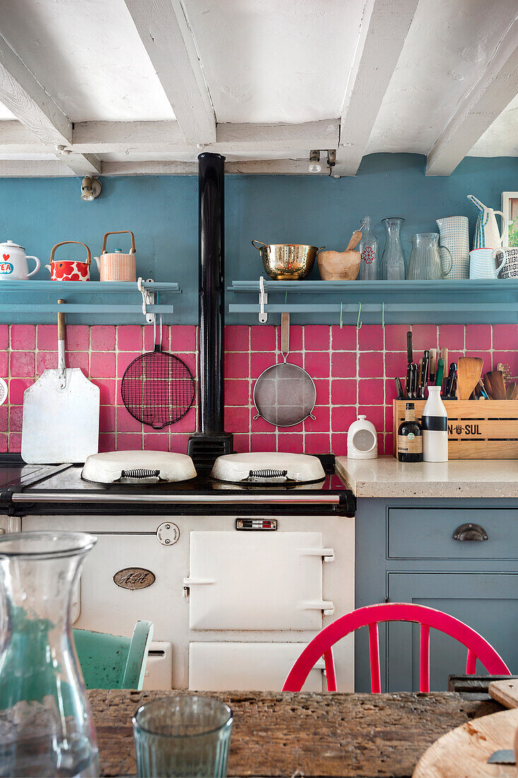 Country-style kitchen with blue wall and pink tiled splashback
