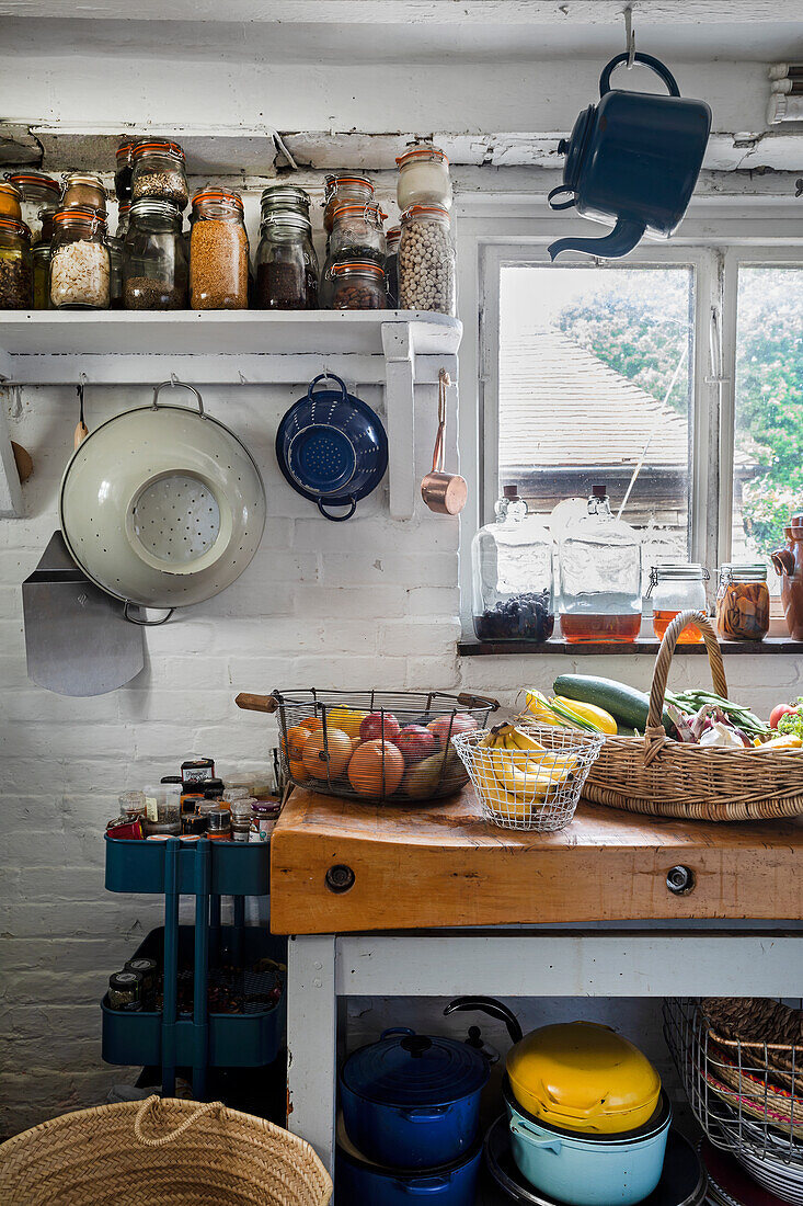 Küchenregal mit Gewürzen und Kochgeschirr neben einem Fenster