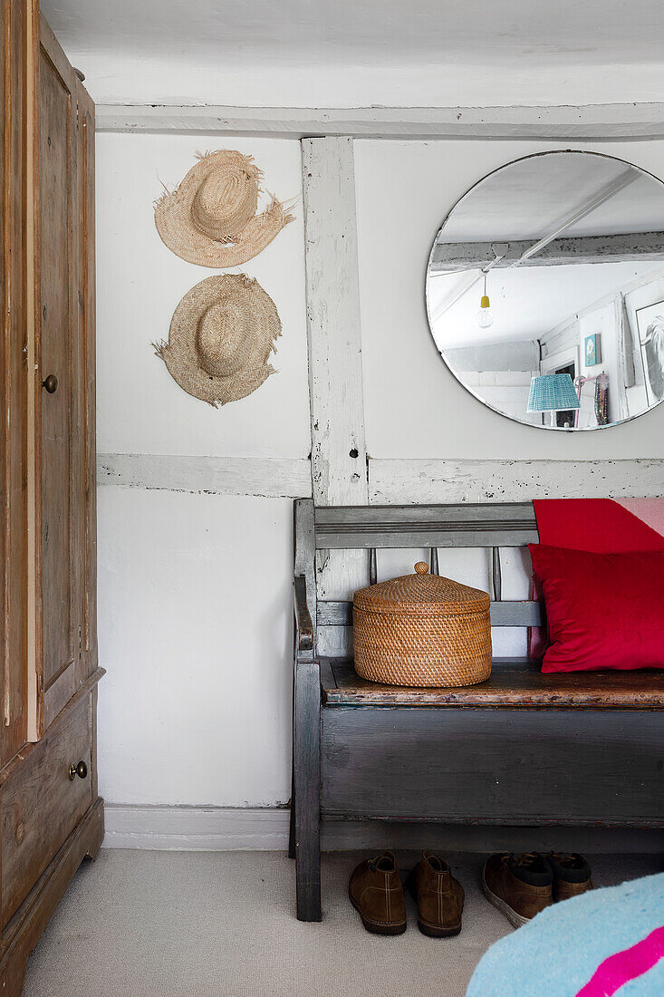 Entrance area with mirror, wooden bench and straw hats on the wall