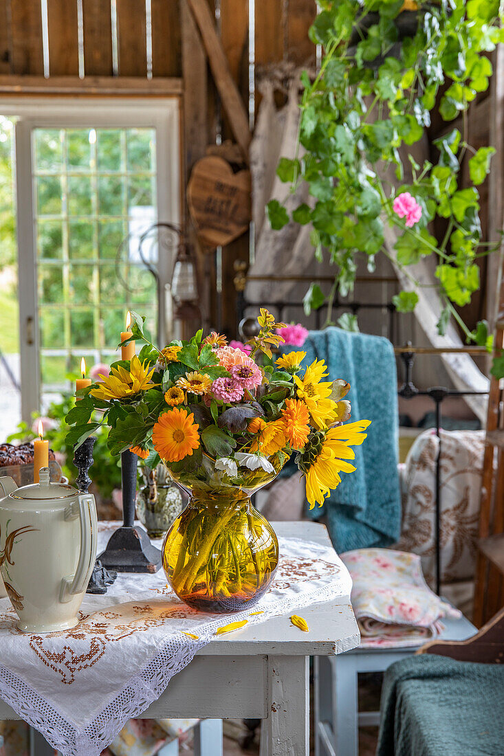 Summery bouquet of sunflowers on table with teapot and candles in garden house