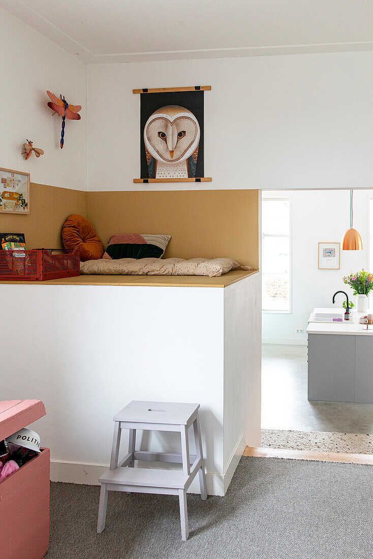 Raised seating area with storage space and owl picture in a bright room