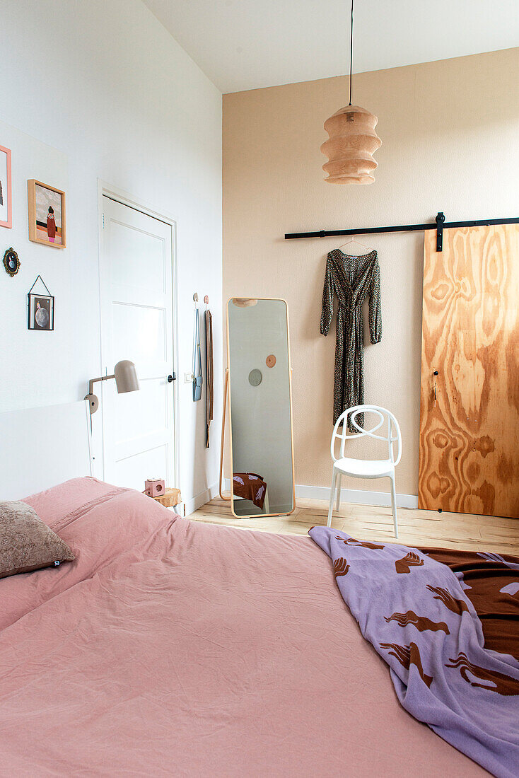 Schlafzimmer mit rosafarbener Bettwäsche und Holzelementen