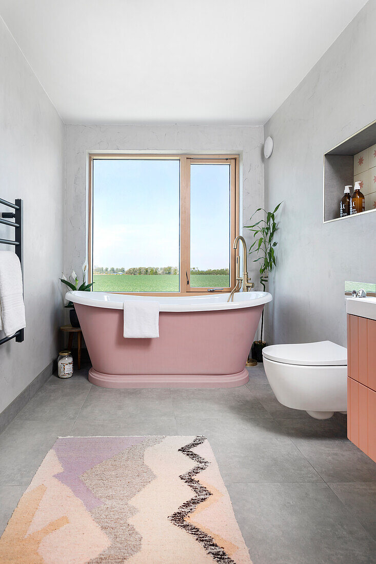 Modern bathroom with pink freestanding bathtub and large window