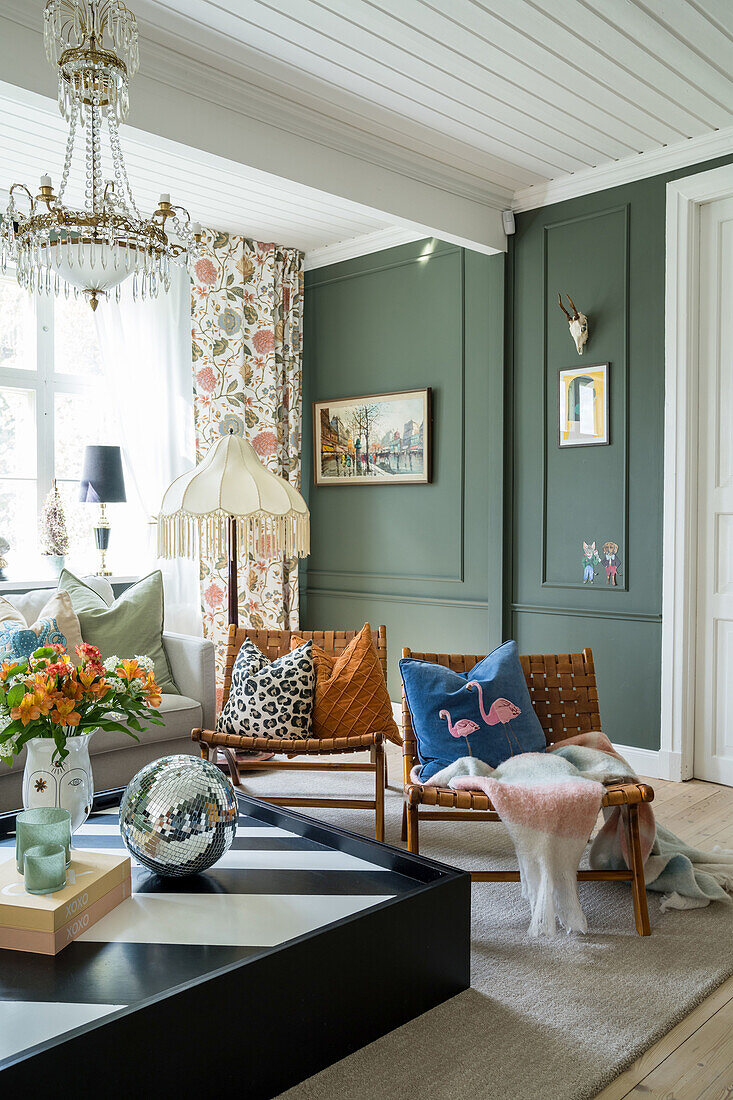 Living room with green wall paneling, leather chairs and vintage decorations