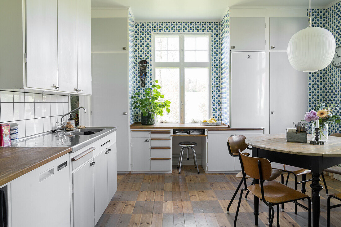 Kitchen with wooden floor, white cabinets and patterned wallpaper