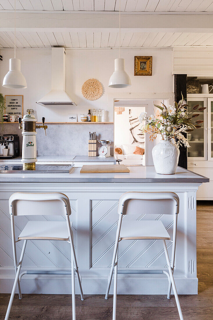 Modern kitchen island with white bar stools and hanging lamps