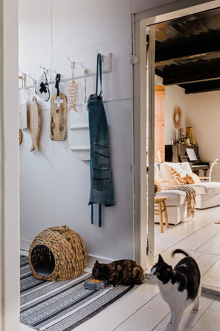 Hallway with cats and decorated coat rack, view of living room with piano