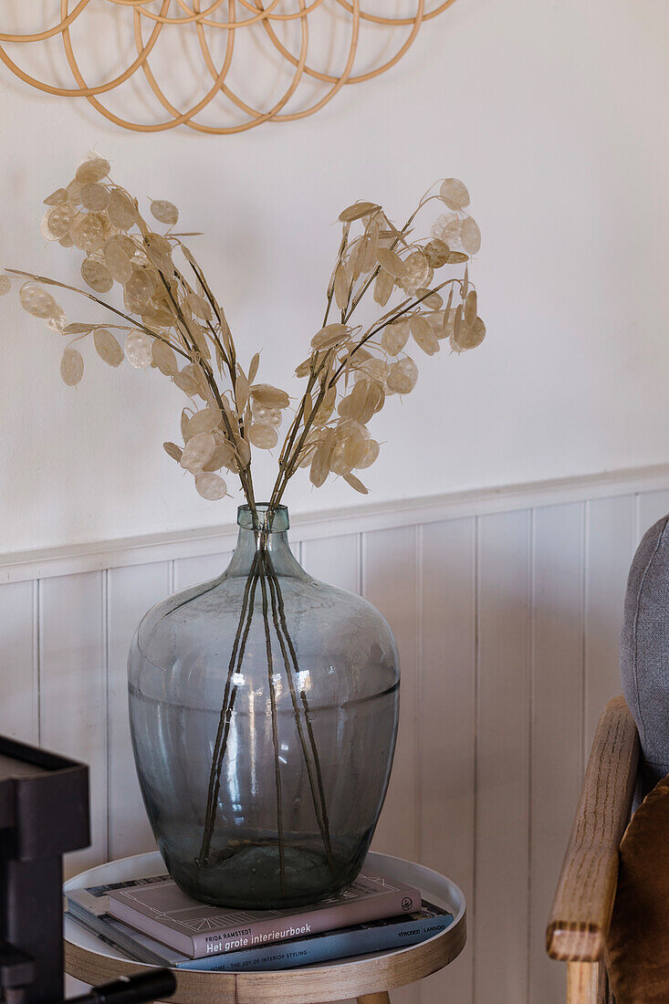 Glasvase mit Trockenblumen auf rundem Beistelltisch im Wohnzimmer