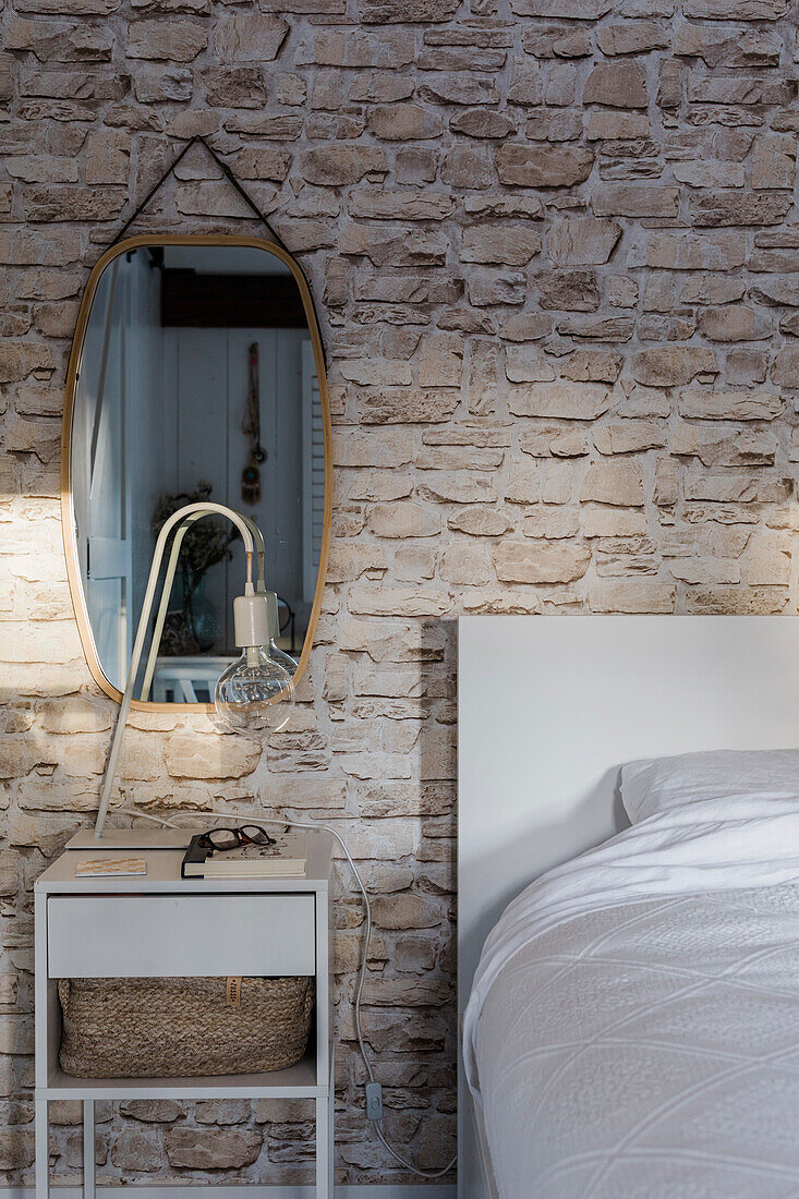 Bedroom with stone wall and modern bed and bedside table in white