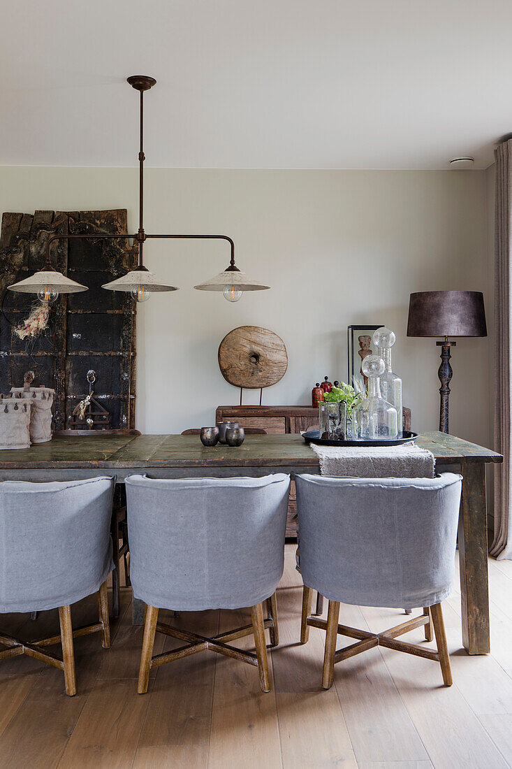 Rustic dining table with grey chairs and decorative glass bottles