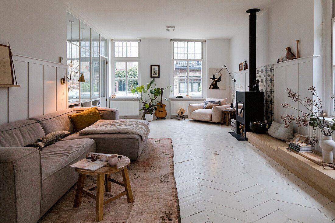 Living room with long, beige-coloured corner sofa and free-standing fireplace