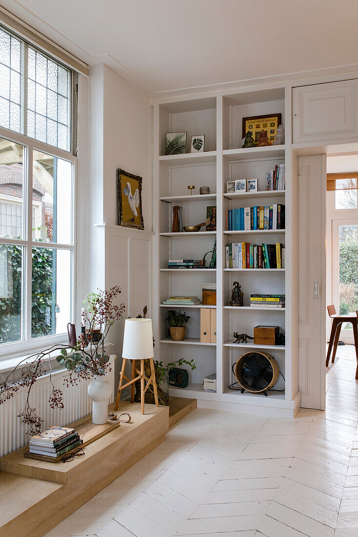 Bright living room with built-in shelving and white floorboards