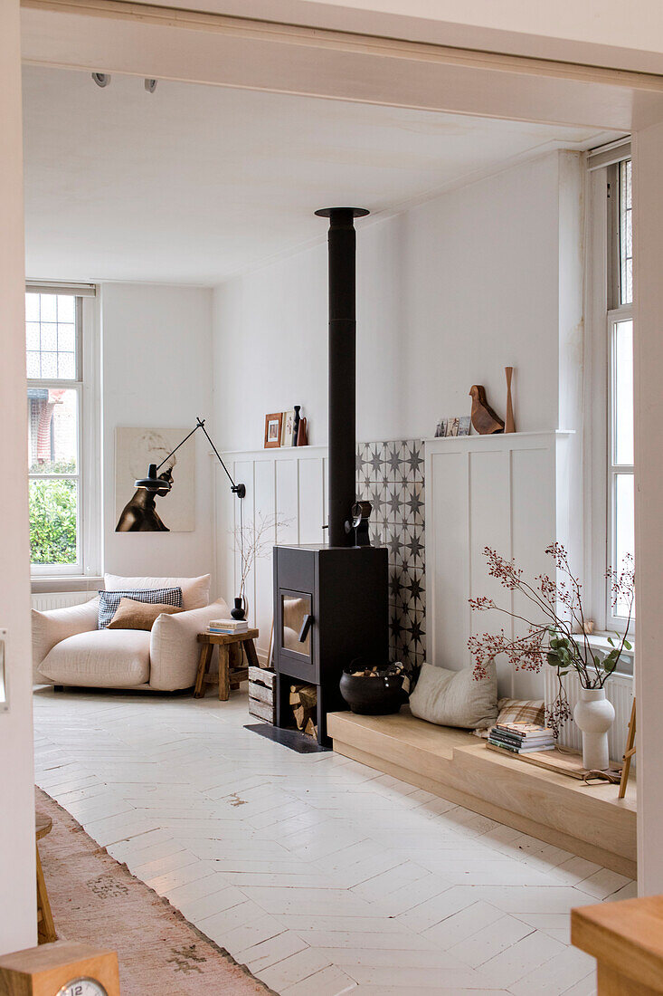 Living room with white wooden floor, modern wood-burning stove and reading corner