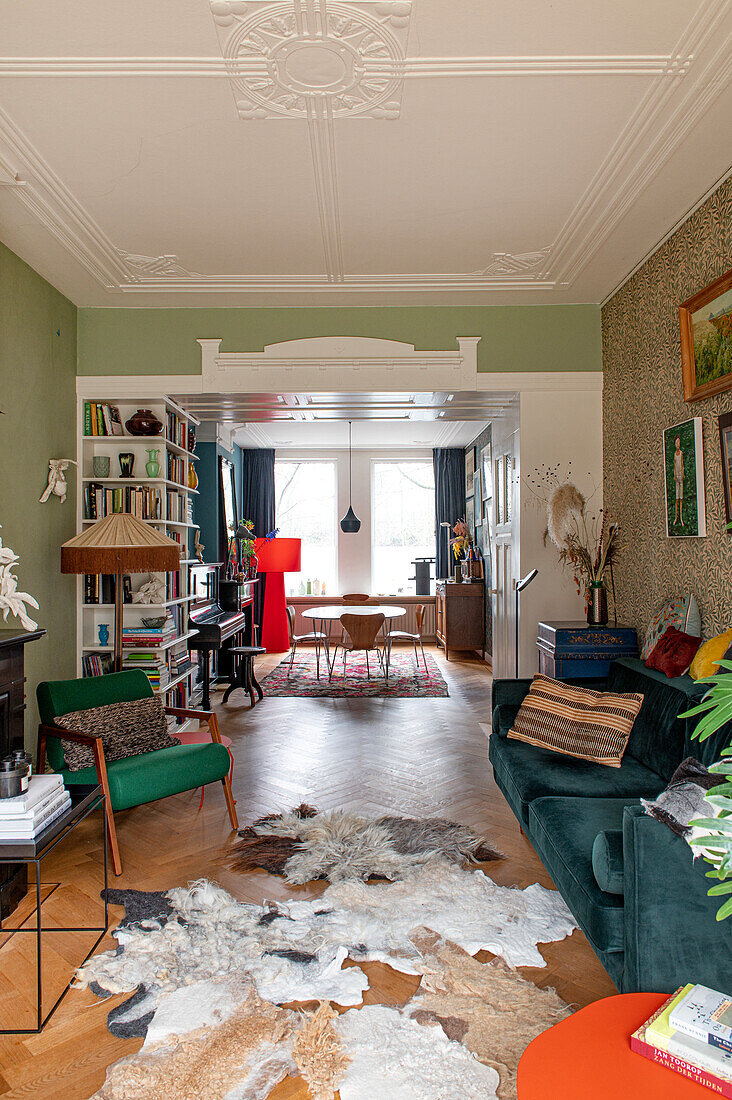 Vintage-inspired living room with green accent wall, bookshelf and parquet flooring