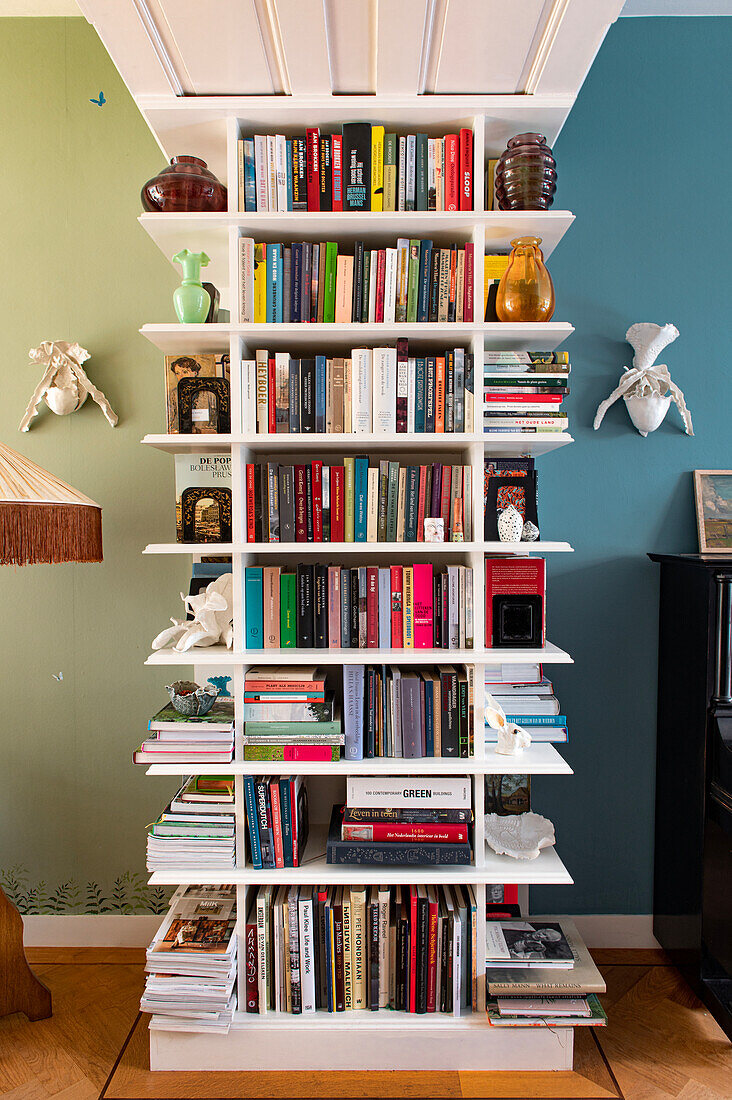 White bookcase with colourful book spines and decorative objects in a living room