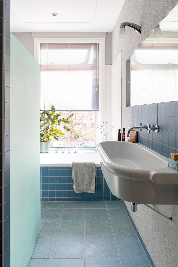 Bathroom with bathtub, blue tiles and large window