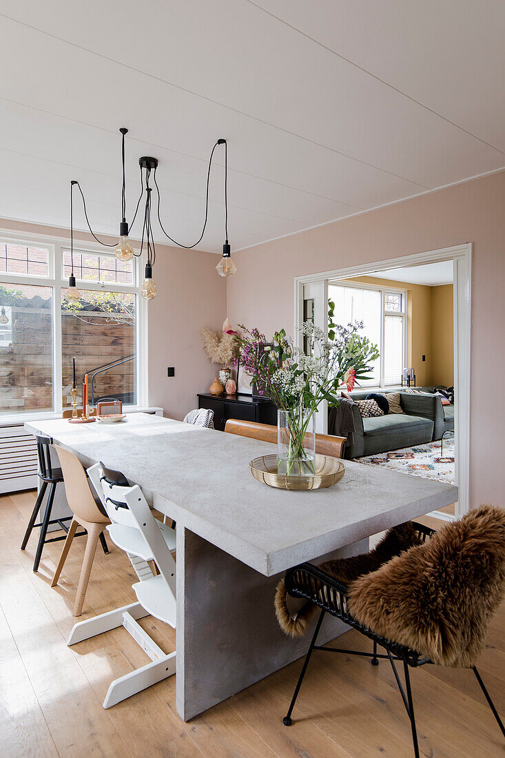 Esstisch mit Betonplatte, moderner Beleuchtung und Blick ins Wohnzimmer