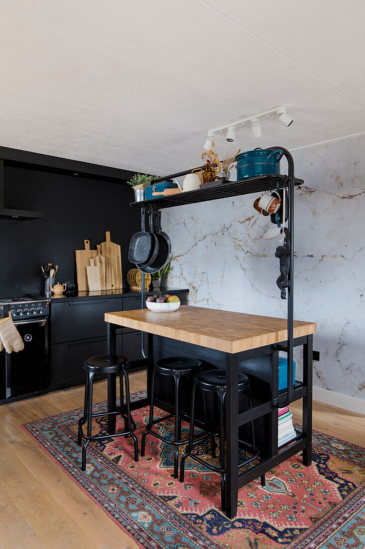 Kitchen island with black high chairs in front of marble wall