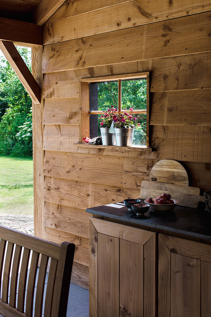 Holzverkleidete Terrasse mit Blumendekoration auf Fensterbank