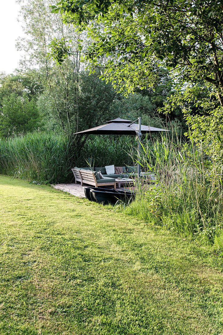 Sitzbereich mit Sonnenschirm und Loungemöbeln im Garten