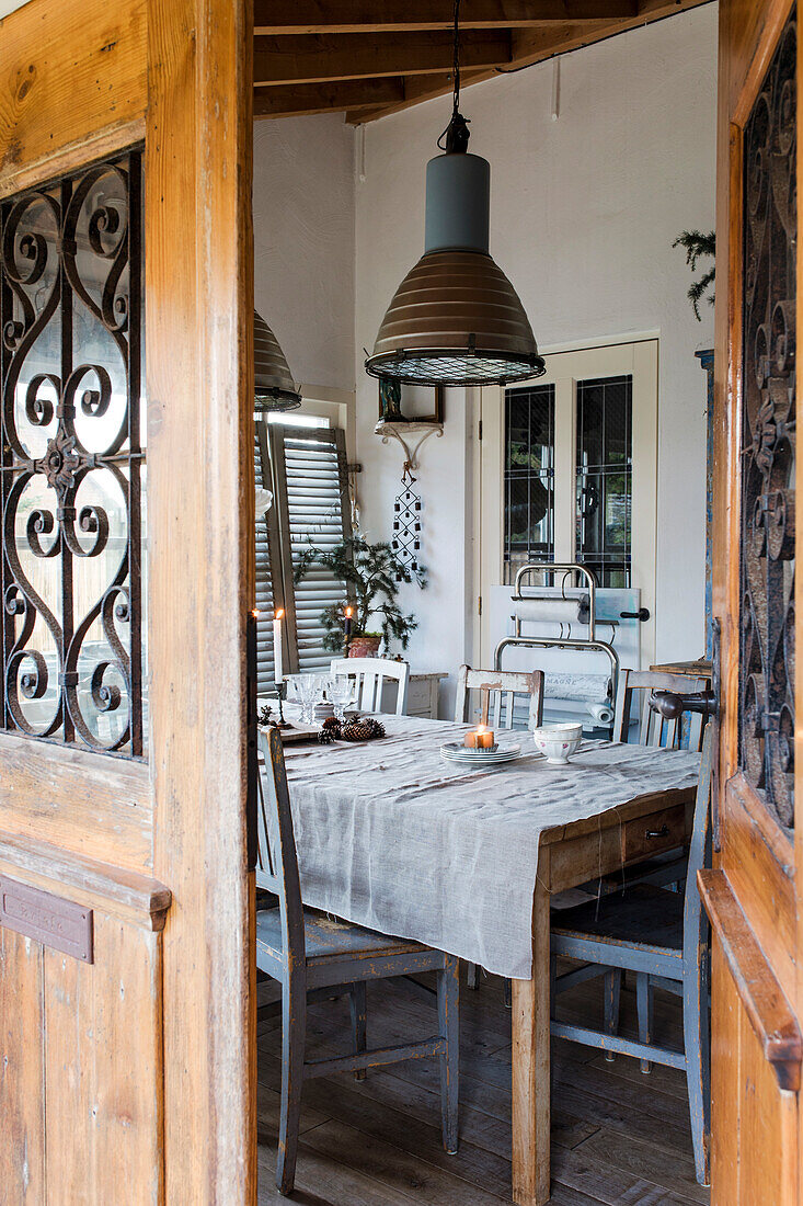 Rustikaler Essbereich mit Holztisch und Hängeleuchten in der Veranda