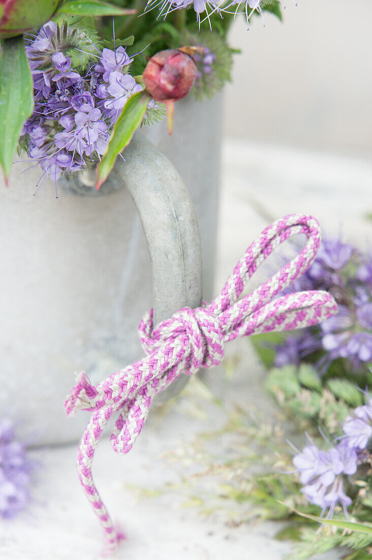 Watering can with bow on handle and bouquet of bee's friend (Phacelia) flowers