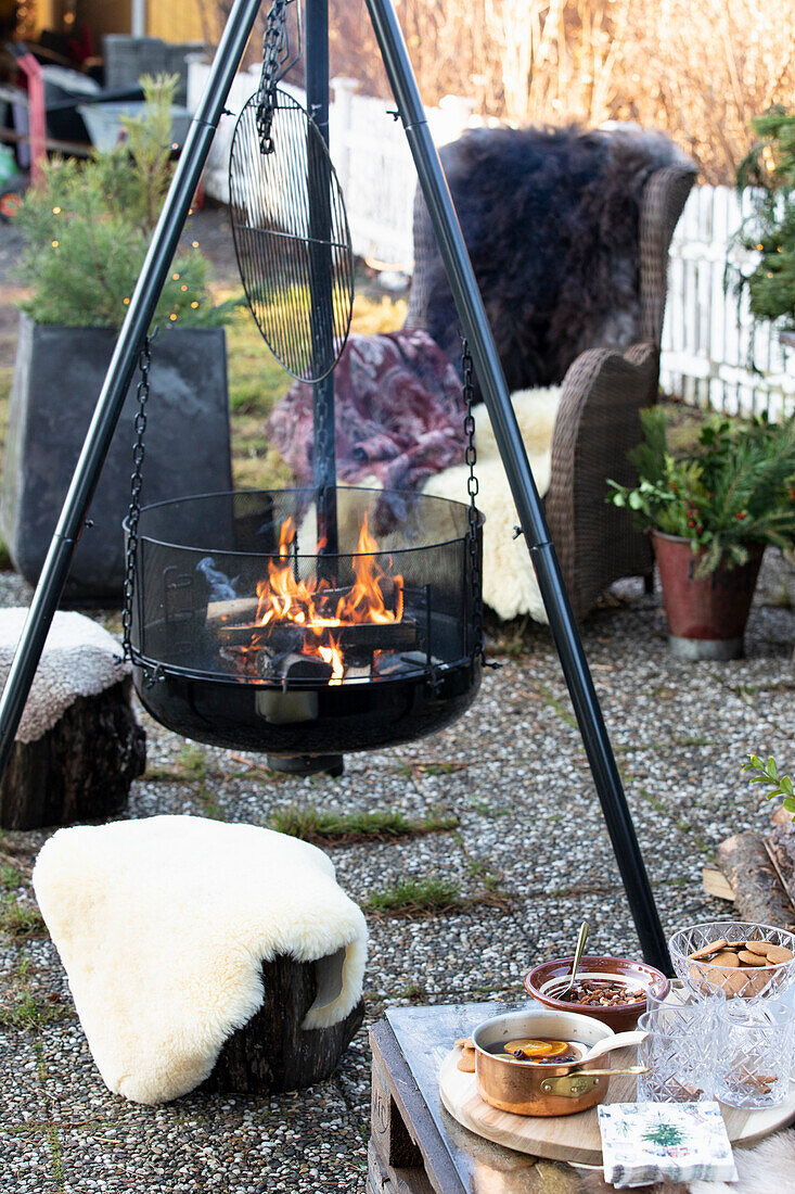 Feuerstelle im Garten, Hocker und Sessel mit Fellen