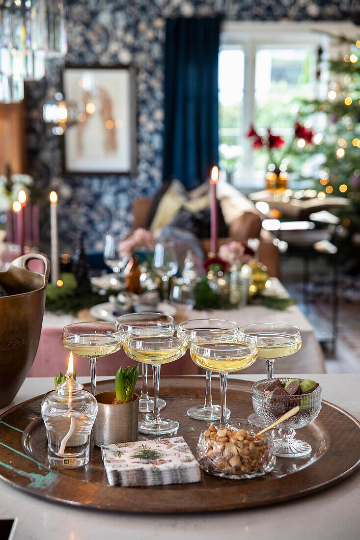 Festively set table with drinks, snacks and Christmas tree in the background