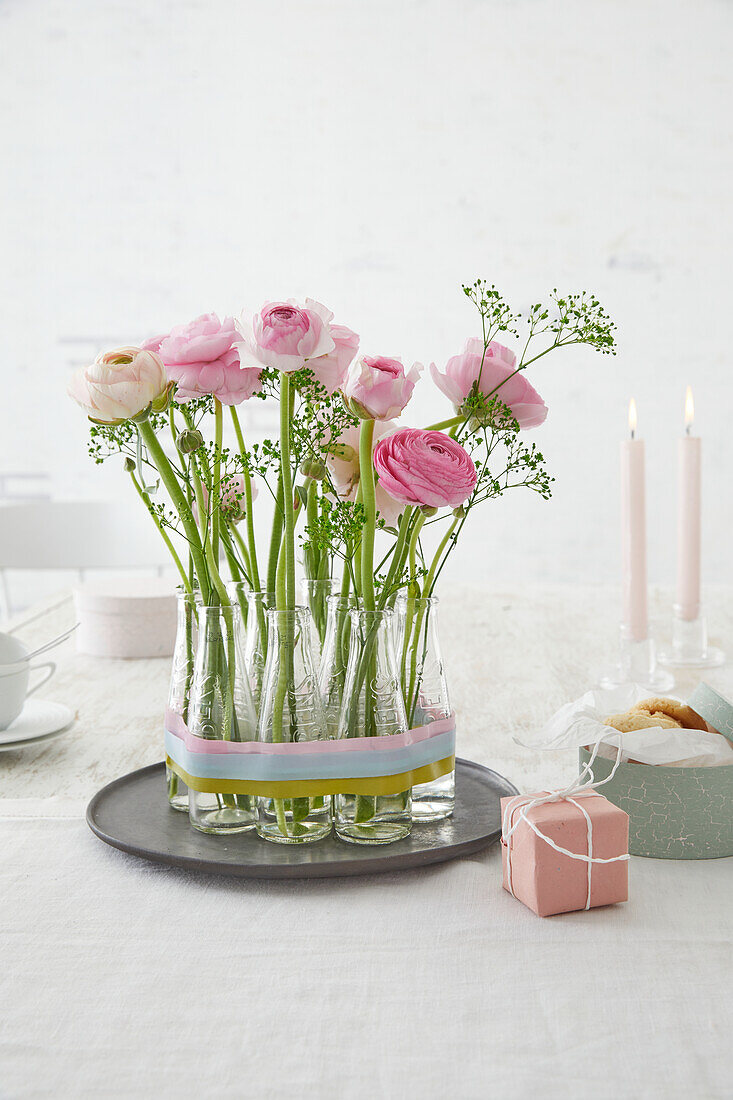 Pink ranunculus in glass vases on a tray