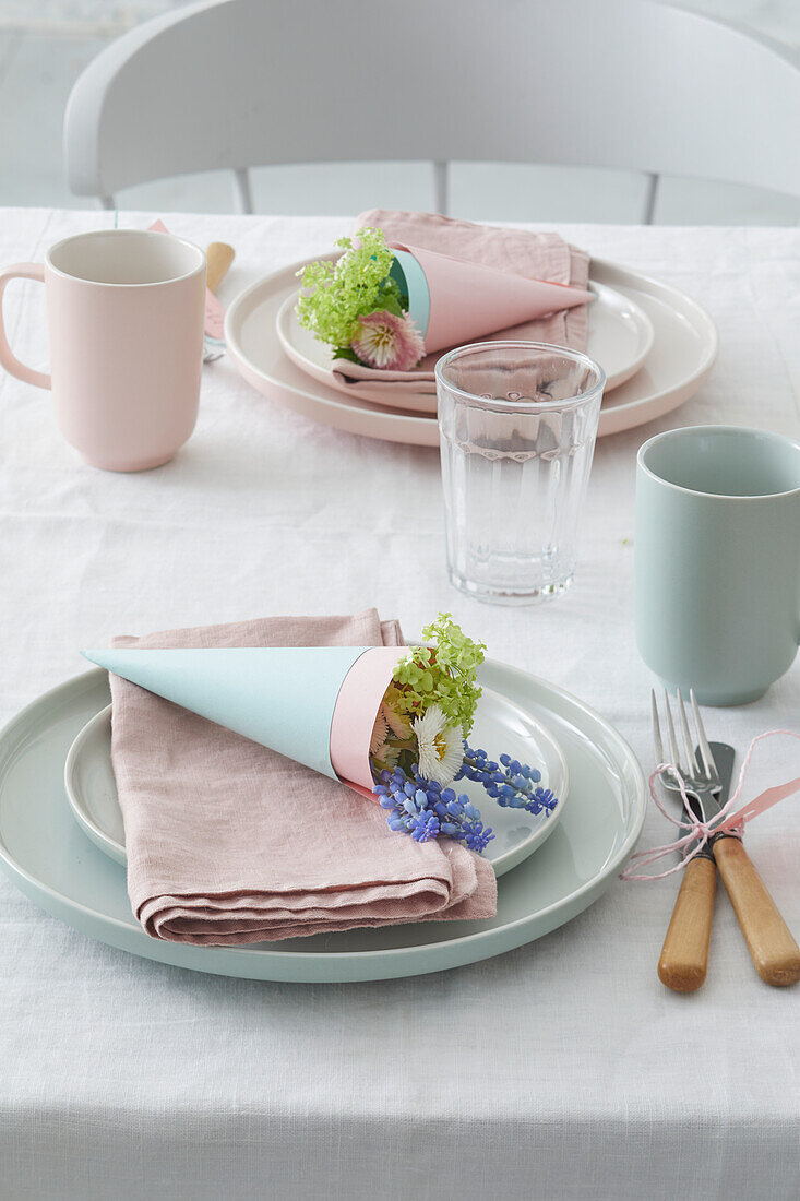 Frühlingshafter Tisch mit pastellfarbenem Geschirr und Blumendeko