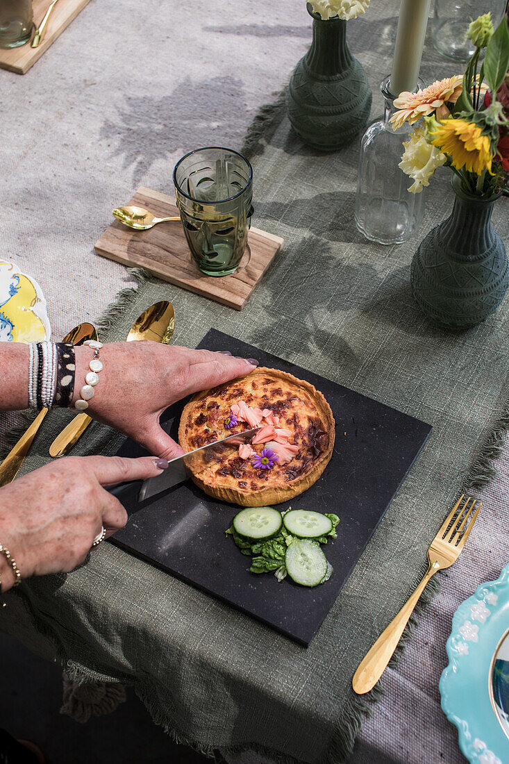 Women's hands cutting tart with edible flowers