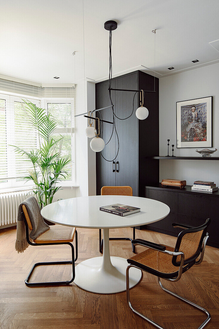 Dining area with tulip table, rattan chairs and modern pendant light