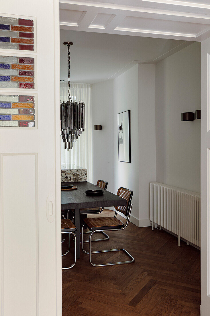 Dining area with wooden table, cantilever chairs and glass chandelier