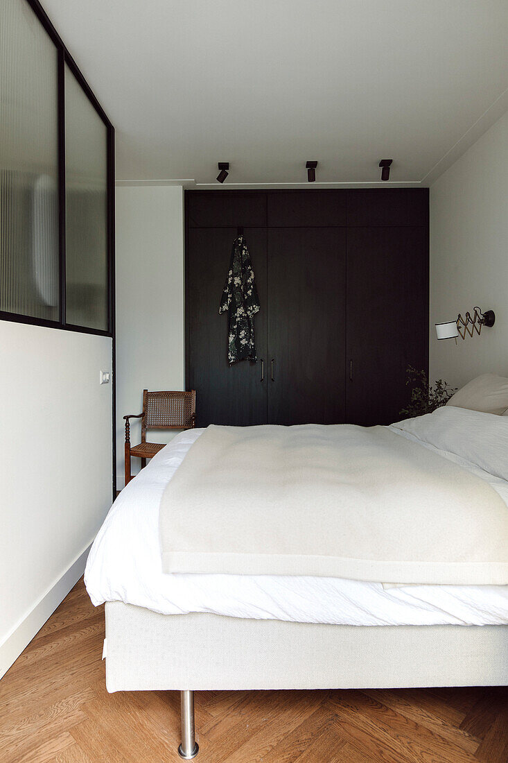 Minimalist bedroom with dark built-in wardrobe and parquet flooring