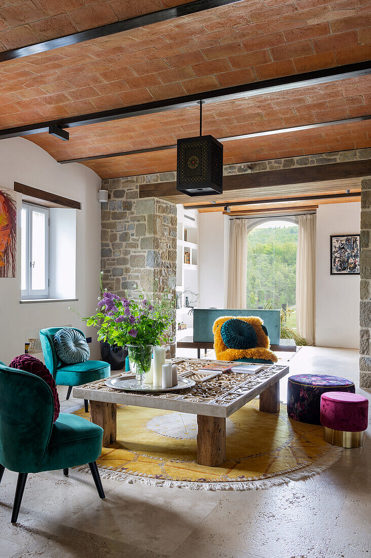 Living room with rustic coffee table, colorful velvet chairs and patterned carpet