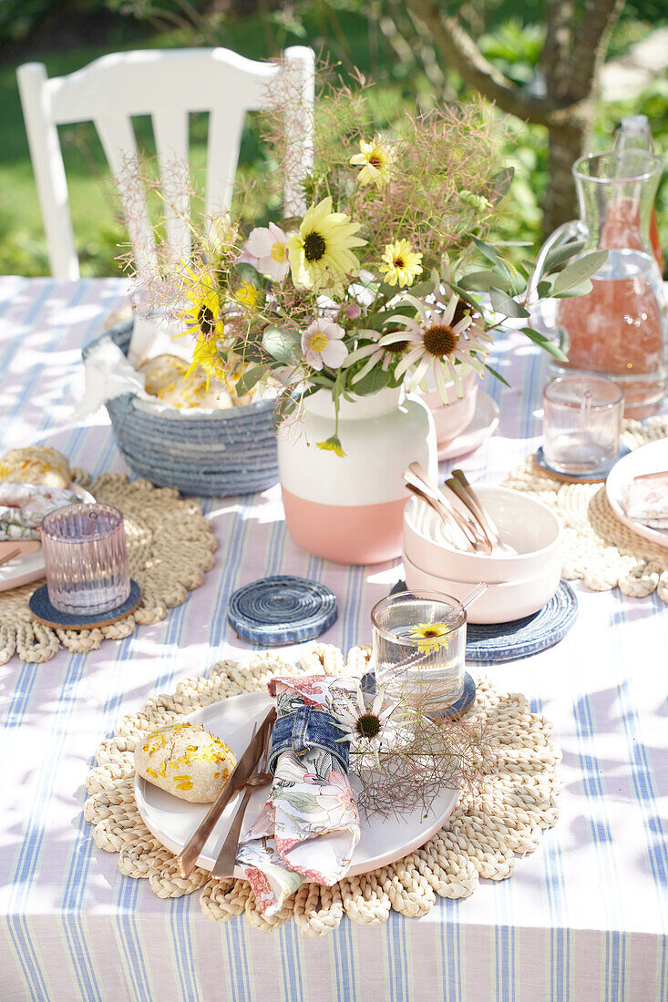 Gedeckter und dekorierter Gartentisch mit Blumenstrauß im Sommer