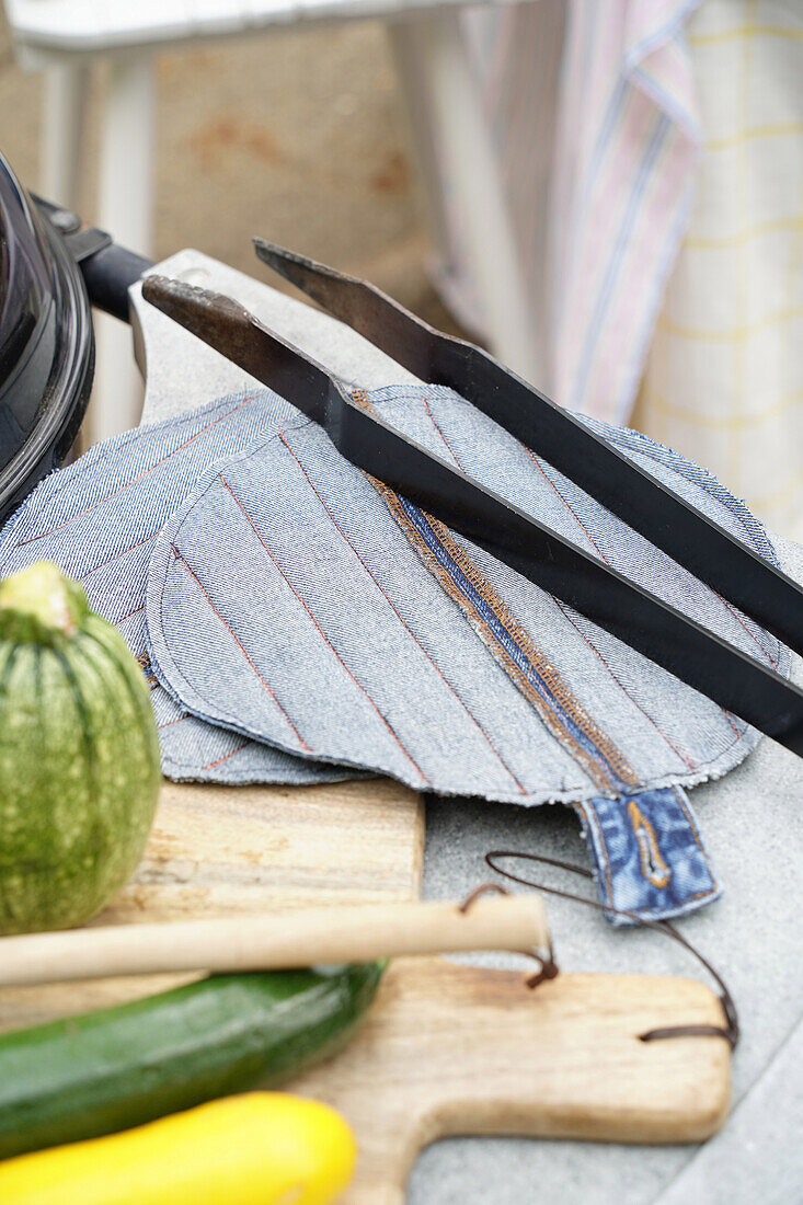 Homemade denim potholders on wooden board next to vegetables