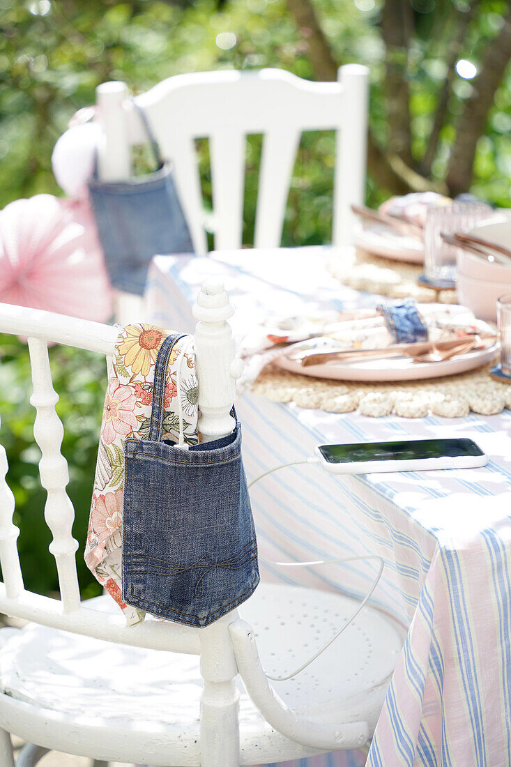 Table in the garden with striped tablecloth and decorated chairs