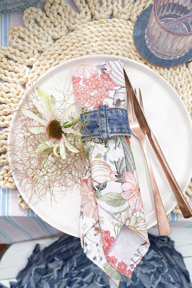 Table setting with floral napkin, white plate and copper cutlery