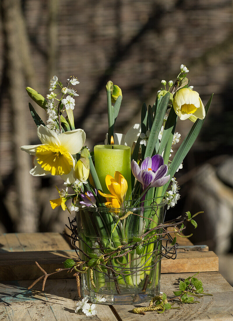 Spring bouquet of daffodils (Narcissus), crocus and plum blossoms, with candle and wreath of birch twigs