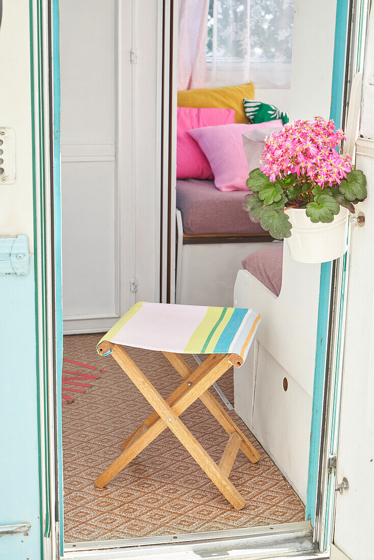 Colorful stool and flowering geranium (Pelargonium) in the camper entrance