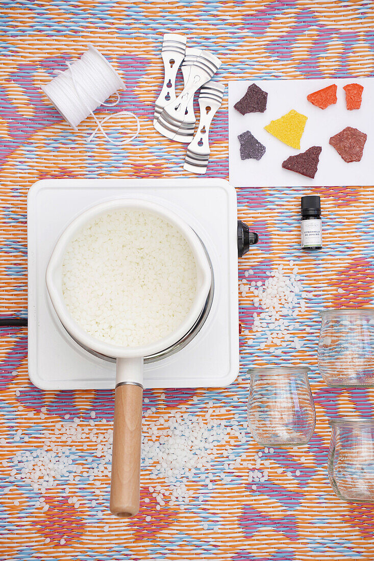 DIY candle making: pot on cooker top, candle wicks and colorful pieces of wax