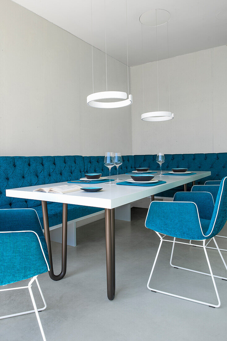 Dining room with blue velvet sofa, white table and blue upholstered chairs